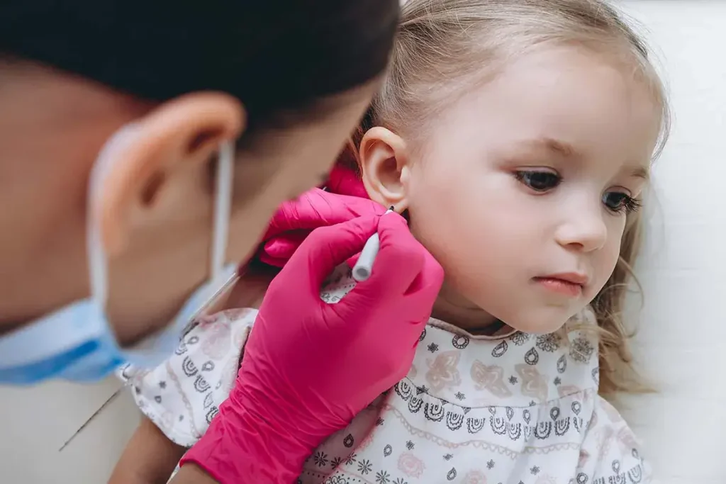 Young girl being marked by professional for a gun free ear piercing.