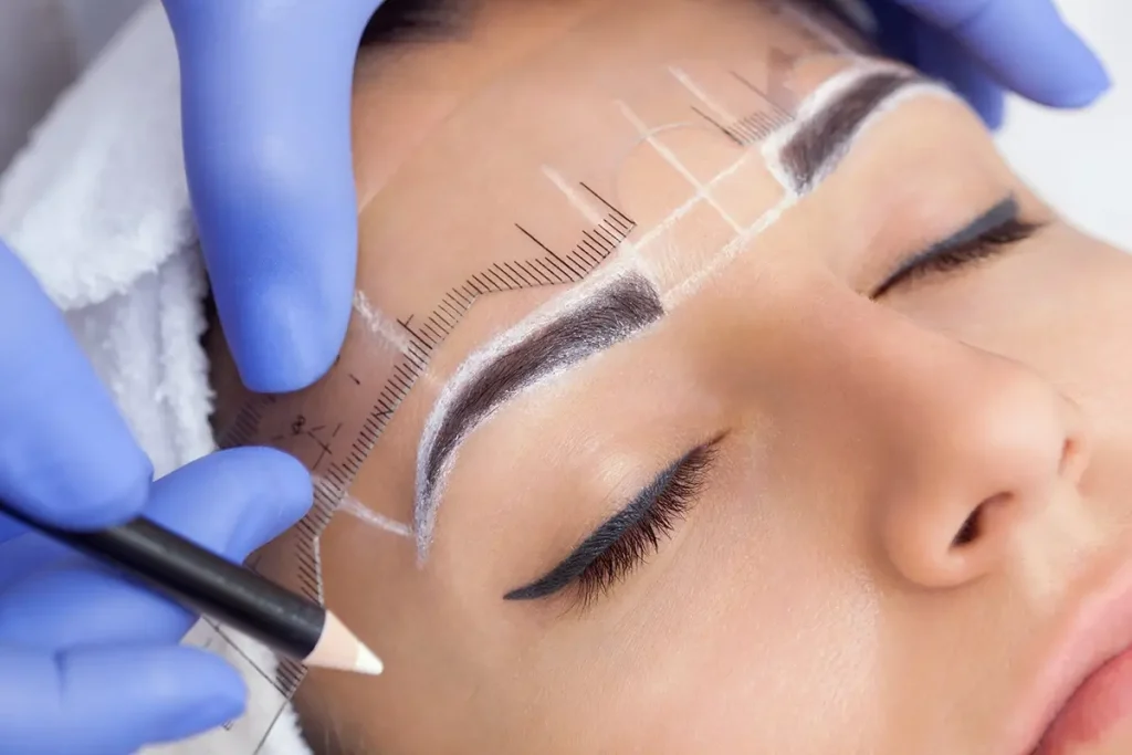 Womans face with hands marking it with a white pencil for microblading